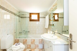 Een badkamer met een douchecabine, een bad, een wastafel en een toilet.