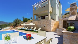 A modern villa with a pool, outdoor seating, and a stone facade. - Villas in Crete with Private Pool & Beaches (Achlades)