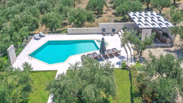 Vista aérea de una propiedad con piscina, sillas de descanso y un patio cubierto.
