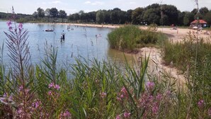 A lakeside view with boats, a sandy beach, and a small building. - Terraced Home in Netherlands near Veluwe (Voorthuizen)