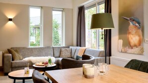 A modern living room with a grey sofa, a wooden coffee table, and a lamp. - Terraced Home in Netherlands near Veluwe (Voorthuizen)