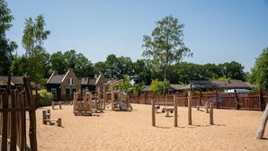 A playground with sand, wooden play structures, and a wooden fence. - Terraced Home in Netherlands near Veluwe (Voorthuizen)