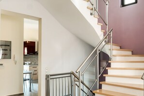 A modern staircase with a glass railing and wooden steps leading to an upper floor.