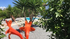 Un espace piscine avec une eau d’un bleu limpide, entouré de différentes plantes et arbres.