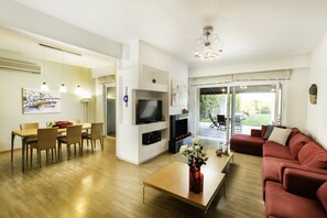 A modern living room with a TV, seating area, and a dining space.
