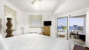 A bedroom with a large bed, a television, a dresser, and a balcony with a view of the sea. - Villa on Island with Private Pool (South Rhodes)