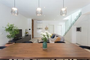 Enjoy meals at the dining table surrounded by lush greenery and a glass staircase leading to an upper level.