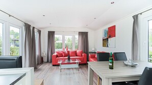 Una sala de estar moderna con un sofá rojo, una mesa de centro y un comedor con mesa y sillas.
