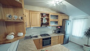 A modern kitchen with wooden cabinets, a gas stove, a microwave, and a refrigerator.