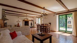 Amplia sala de estar con piso de madera, un sofá con cojines rojos, una mesa de comedor y una chimenea.