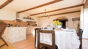 Un comedor rústico con una isla de ladrillo, vigas de madera y una chimenea de piedra.