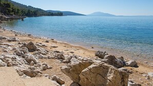 A rocky beach with clear water and distant mountains. - Villa in Cres with Sea Views & Pool (Martinšćica)