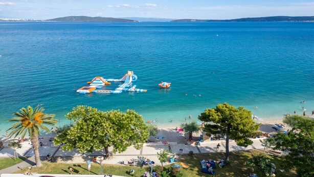 Ein Strand mit aufblasbaren Wasserrutschen und einem klaren, blauen Meer.