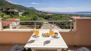 Ein Balkon mit Frühstückstisch, mit Blick auf eine reizvolle Landschaft aus Häusern und Bergen.