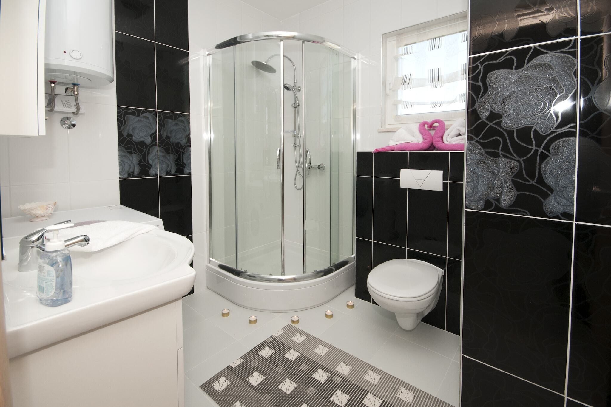 A modern bathroom with a glass-enclosed shower, a white sink, and a toilet.