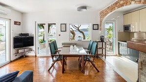 Ein geräumiger Wohnbereich mit einem Holzespeisetisch, blaugrünen Stühlen, einem Flachbildfernseher und einer Wand mit Steinverkleidung.