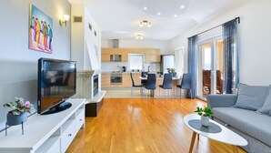 Una sala moderna con televisor de pantalla plana, un sofá, una mesa de centro y un comedor con sillas.