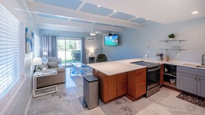 A modern kitchen with a central island, built-in oven, and a flat-screen TV mounted on the wall. - Recent remodel - Large 1BR w/ ocean view and walk to excellent beaches/eateries (Kihei)