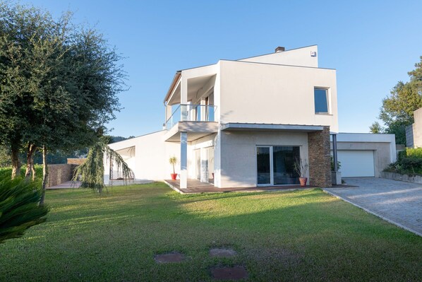 A modern two-story house with a balcony, a garage, and a well-maintained lawn.
