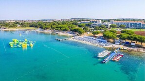 An aerial view of a coastal area with a marina, boats, and a large building with multiple floors. - Apartment in Ližnjan with Pool and Terrace (Ližnjan)
