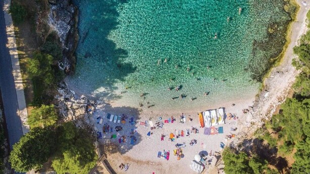 An aerial view of a beach with clear turquoise water, a sandy shore, and several colorful umbrellas and beach chairs. - Apartment in Ližnjan with Pool and Terrace (Ližnjan)