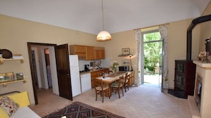 Una cocina compacta con armarios de madera, una mesa de comedor con sillas, un refrigerador y un microondas.