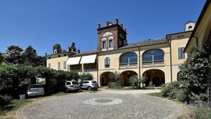 Un patio con un diseño circular de piedra, autos estacionados y un edificio con ventanas arqueadas y una torre.