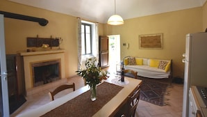 Un comedor con chimenea, una mesa con un florero, un sofá y una alfombra estampada.