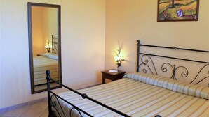 A bedroom with a bed, a nightstand, a mirror, and a painting on the wall. - Country Farmhouse, Casperia (Casperia)