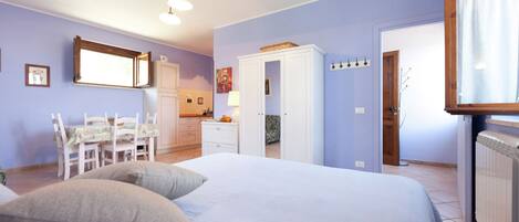 Ein Schlafzimmer mit einem Bett, zwei Kissen, einem Schreibtisch mit Stuhl, einem Kleiderschrank und einem Fenster.
