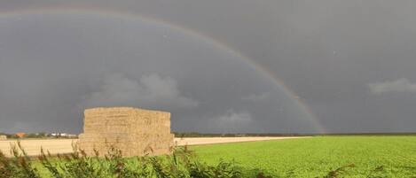 A rural landscape with a haystack and a rainbow.