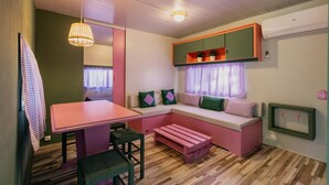 A compact living space with a dining table, bench seating, a built-in sofa, and a hanging light fixture. - Stylish Chalet in Mont-roig (Mont-Roig del Camp)