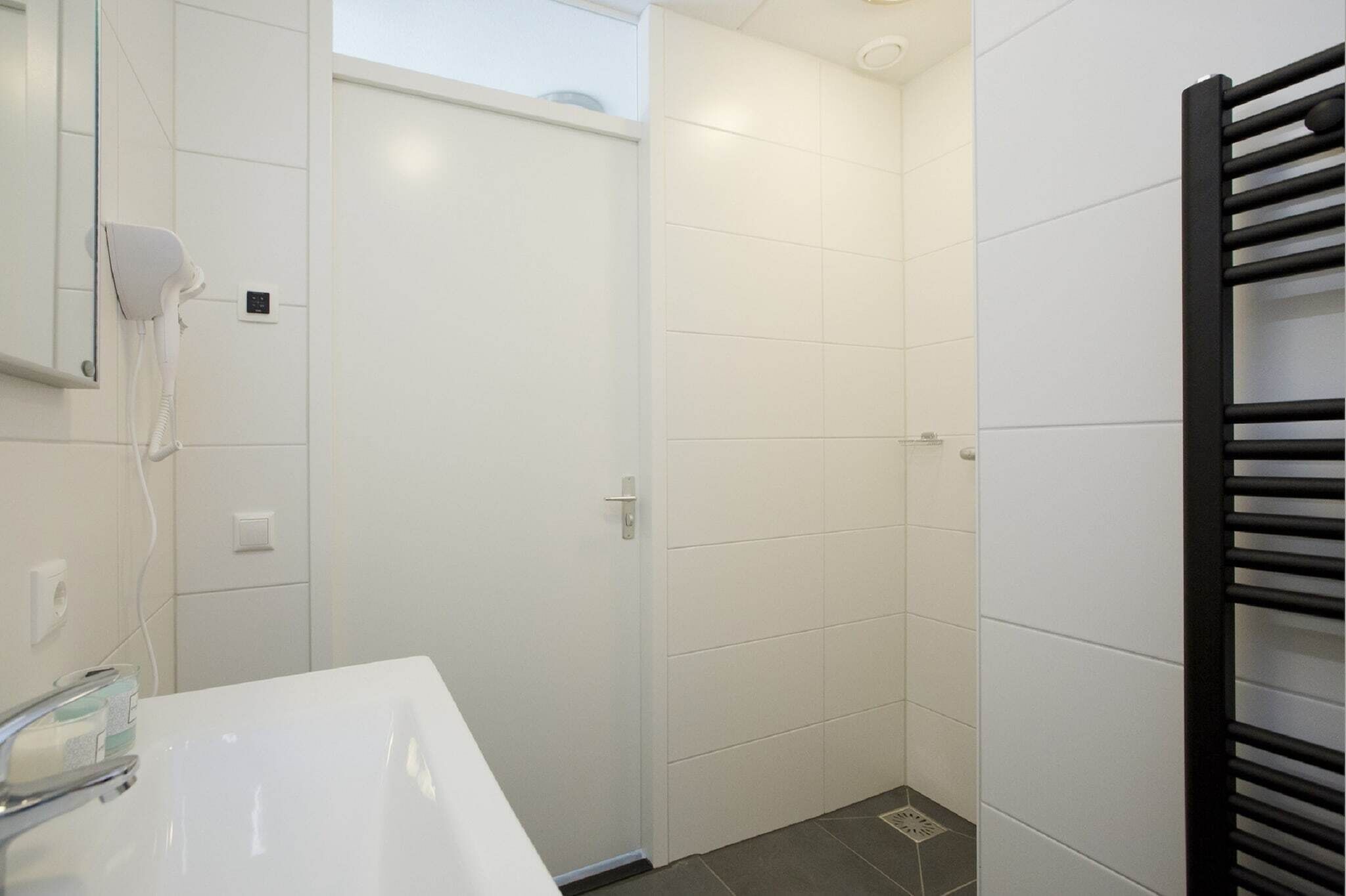 A bathroom with a white sink, a hairdryer, and a towel rack.