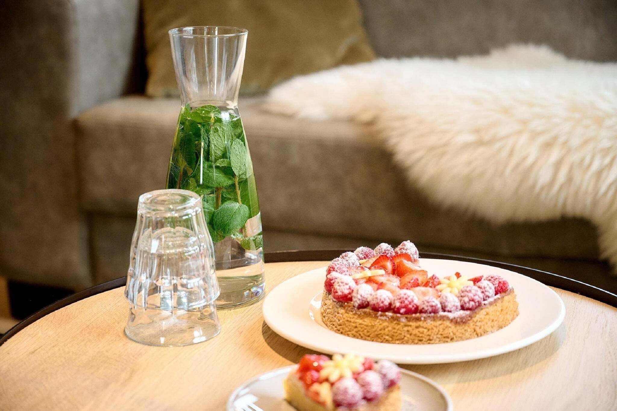 Una mesa con una jarrón de vidrio, un vaso y dos platos de postre.