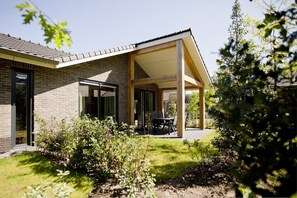 Une maison moderne dotée d’un patio couvert, d’une façade en briques et d’un jardin.