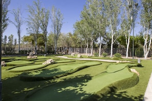 Ein gepflegter Golfplatz mit ordentlich gestutztem Rasen, Felsformationen und Bäumen.