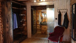 A log cabin interior with a wooden wardrobe, a red velvet chair, and a mirror on the wall. - Holiday Home in Netherlands with Pond View (Baarle-Nassau)
