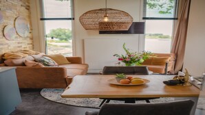 Un espacio de sala acogedor con un sofá, una mesa de comedor con fruta y una lámpara colgante.