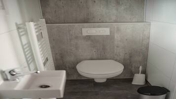 A bathroom with a toilet, sink, and a trash bin.
