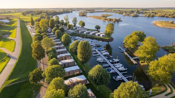 Un hotel a orillas del río con varias edificaciones, un muelle con barcos y una zona ajardinada bien cuidada.