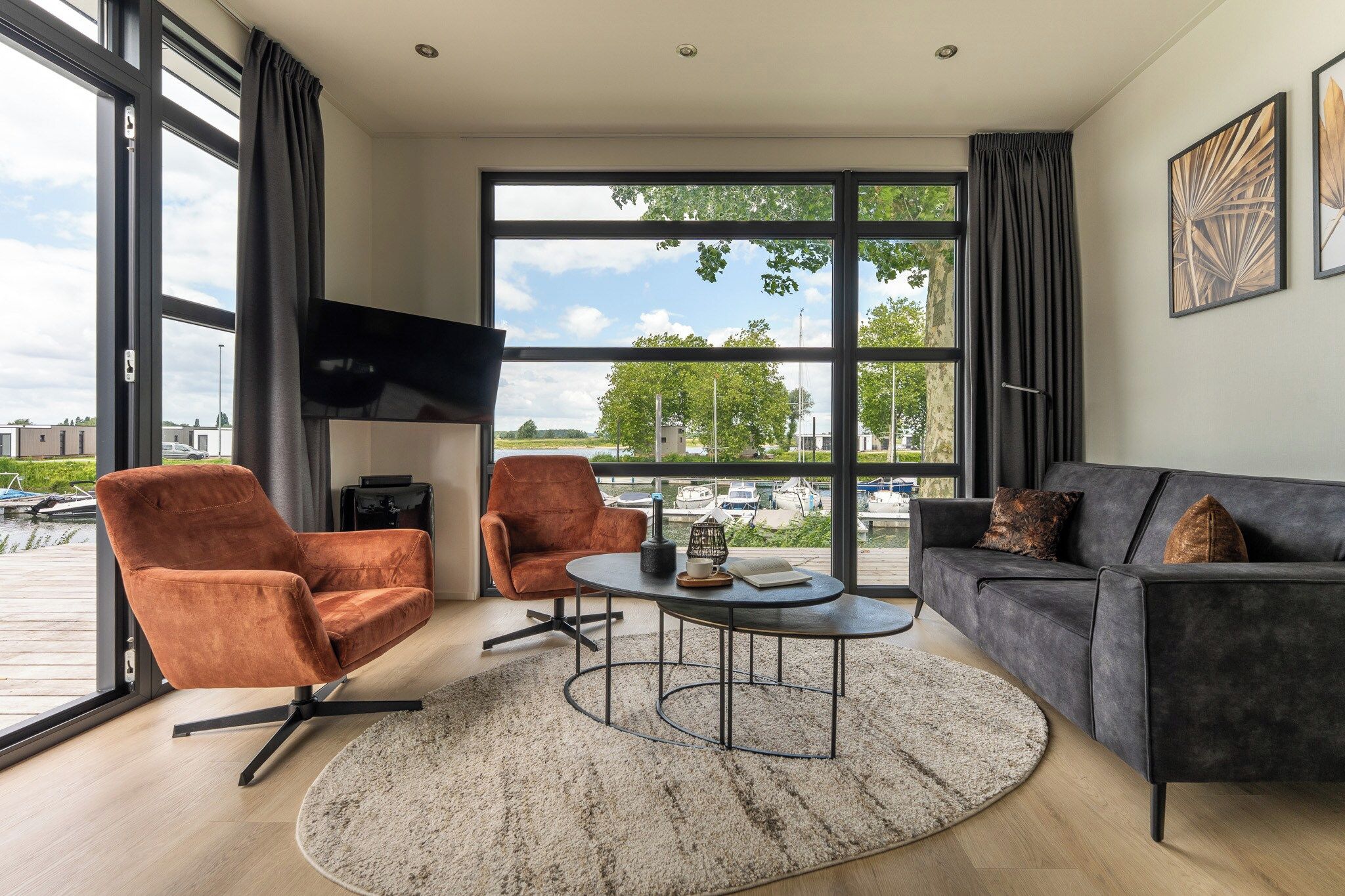 A modern living room with a sofa, two armchairs, a coffee table, and a TV.