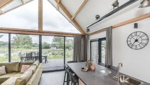 A modern kitchen with a large window, a dining area with a sofa, and a view of a garden.