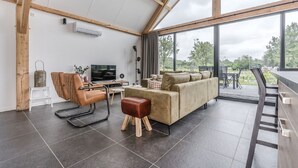 A modern living room with a sofa, a television, and a dining area with a table and chairs.
