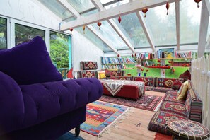 Relax in a spacious room with a high ceiling, large windows, and a comfortable sofa.