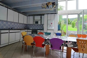 Enjoy meals in the spacious dining area with a large table and comfortable chairs, surrounded by a view of the outdoors.