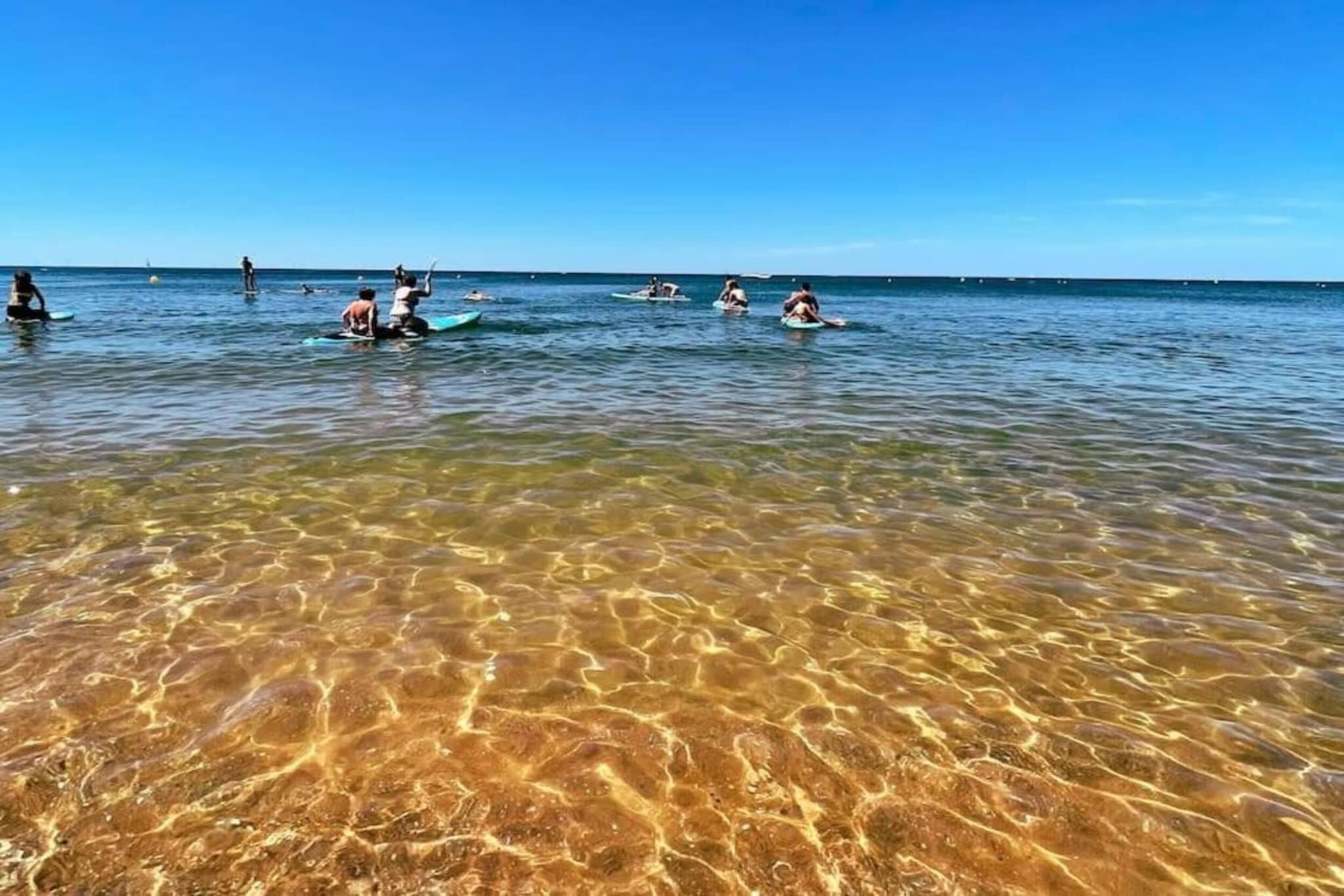 A beach scene with clear shallow water and people in the distance.