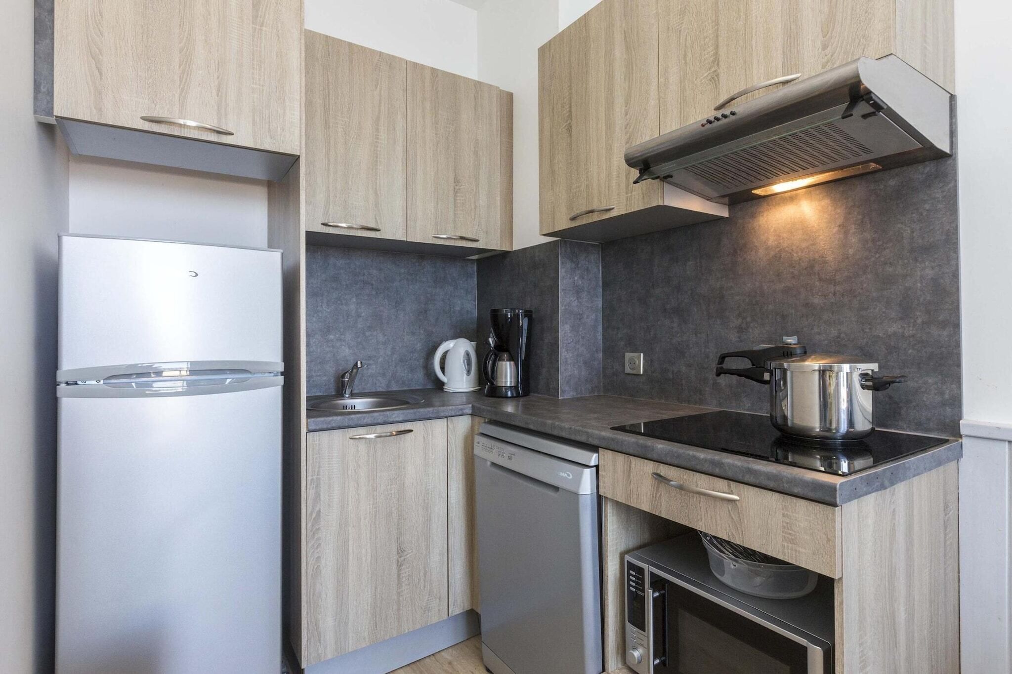 Cocina compacta con lavavajillas integrado, estufa y cafetera.