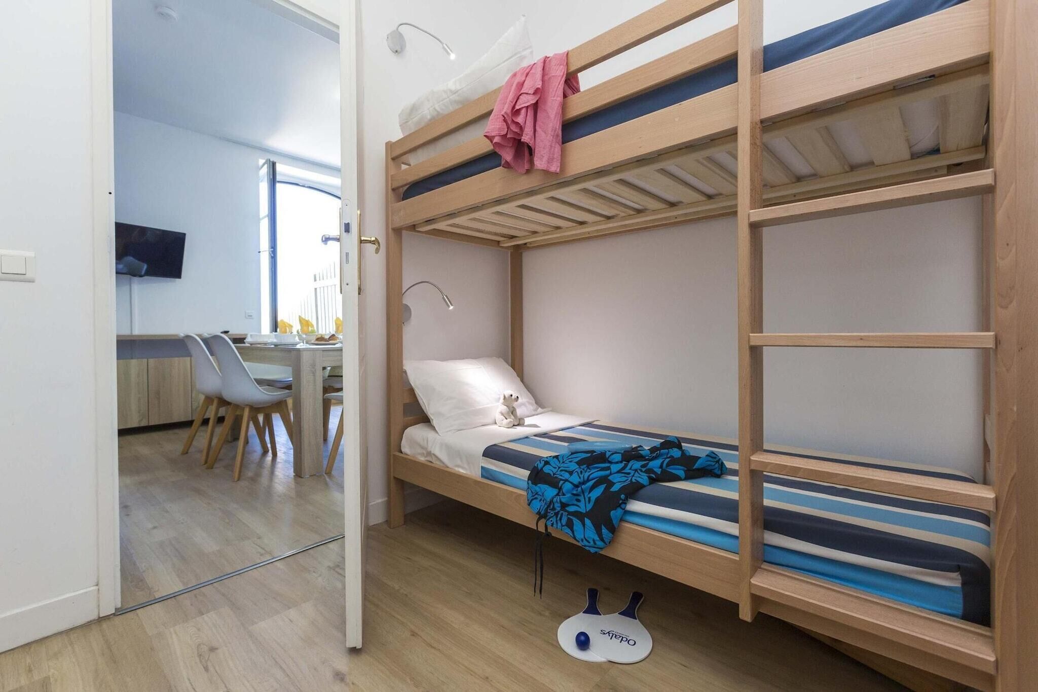 A bunk bed with a desk and chair in the adjacent room.