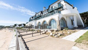 Una propiedad costera con un edificio de dos pisos, un balcón y un camino pavimentado que conduce a la playa.