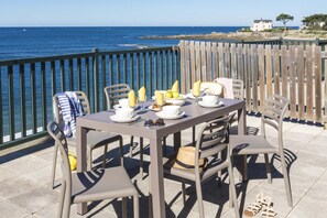 An outdoor dining area with a view of the sea, a wooden fence, and a building in the background. - Apartment in Côte Sauvage near La Baule Bay (Batz sur Mer)